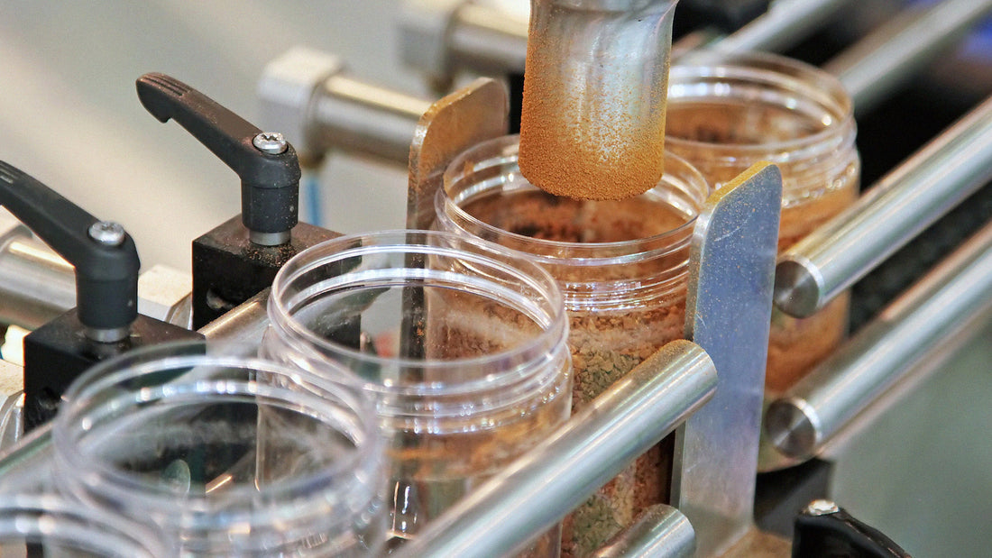 Automated machine filling plastic containers with powdered ingredients on a production line.