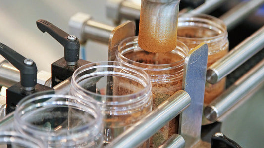 Automated machine filling plastic containers with powdered ingredients on a production line.